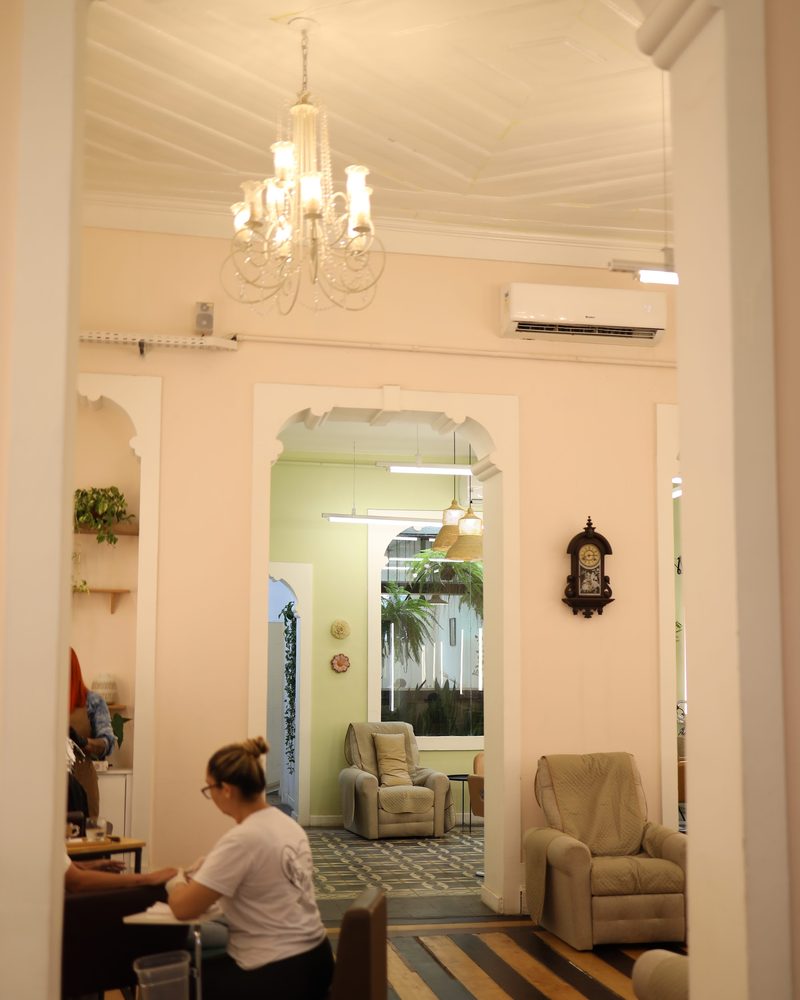 Salão do Constant Benjamin visto da entrada, com lustre de cristal, arcos, poltronas e piso de ladrilho no casarão histórico